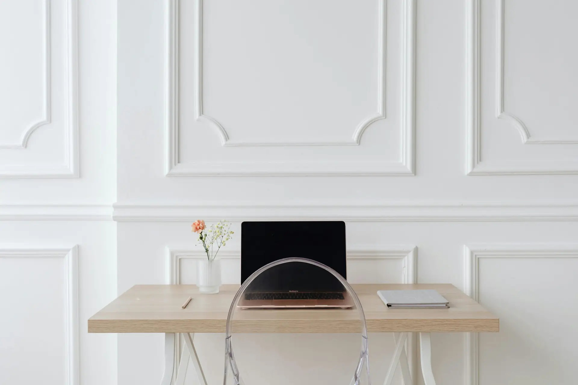 Elegant minimalist office setting with laptop, notebook, and decor on a wooden desk.