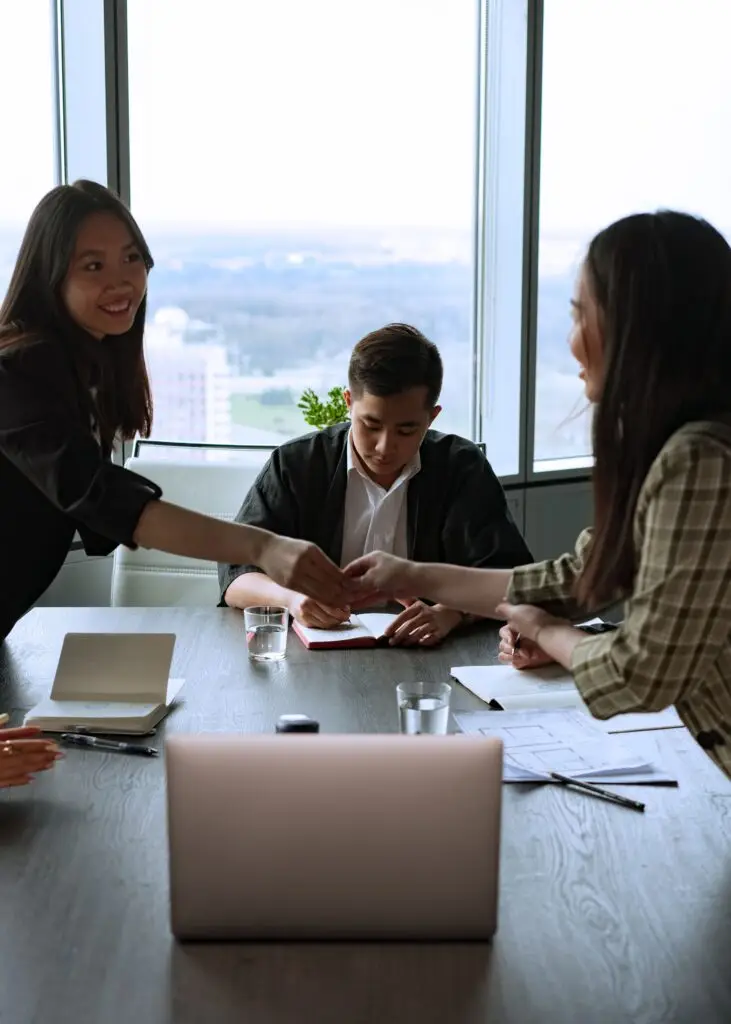 Team members collaborate in a bright office space with a view, using laptops and notes.